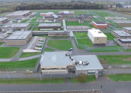 Vue aérienne du complexe carcéral de Donnacona, montrant les bâtiments sécurisés, les clôtures périmétriques et les installations extérieures sur un vaste terrain verdoyant