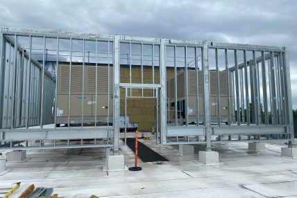 Installation d’équipements mécaniques sur une toiture, avec structure d’acier galvanisé en cours de montage et unités de ventilation de marque Daikin à l’arrière-plan