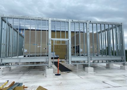 Installation d’équipements mécaniques sur une toiture, avec structure d’acier galvanisé en cours de montage et unités de ventilation de marque Daikin à l’arrière-plan