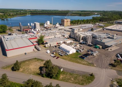 Vue aérienne de l’usine Parmalat à Victoriaville, avec bâtiments industriels, silos, équipements de production et un plan d’eau en arrière-plan