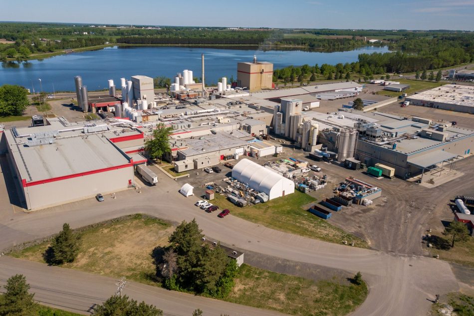 Aerial view of the Parmalat plant in Victoriaville, featuring industrial buildings, silos, production equipment, and a body of water in the background