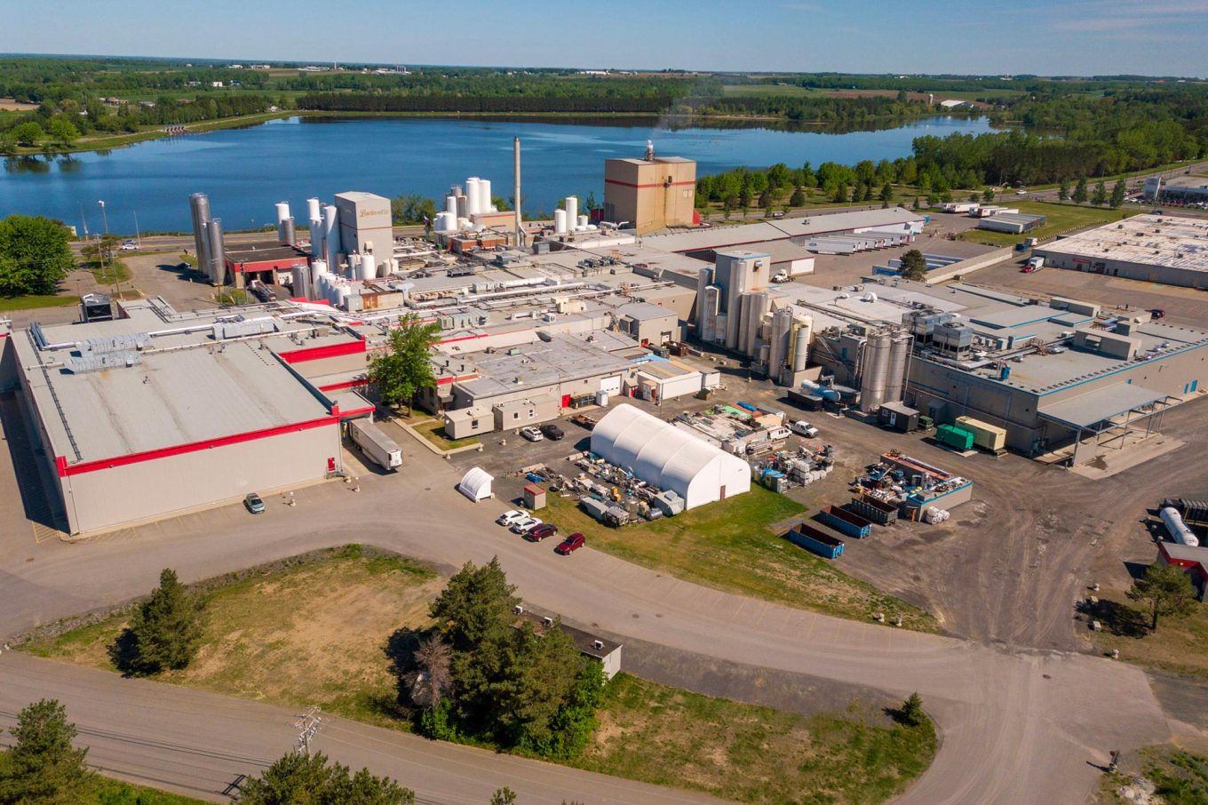 Aerial view of the Parmalat plant in Victoriaville, featuring industrial buildings, silos, warehouses, and a body of water in the background