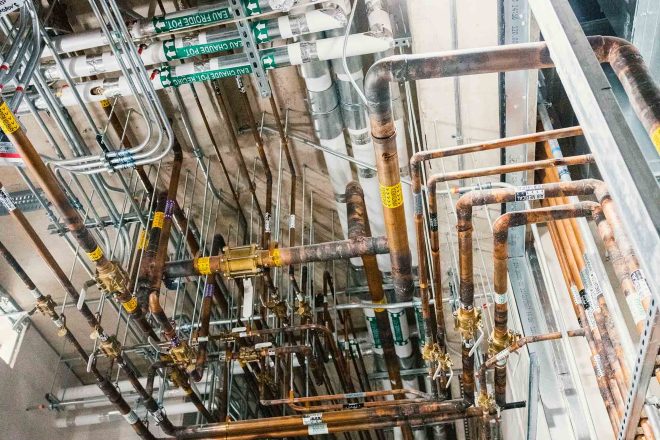 Installation complexe de tuyauterie mécanique au plafond d’un hôpital en construction à Santa Cabrini, incluant eau froide, chauffage et gaz médicaux